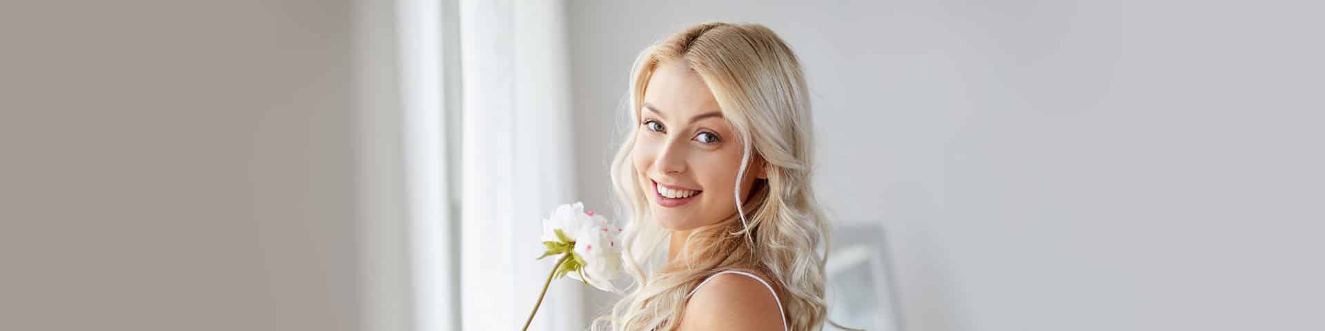 Blonde woman with flower smilling.