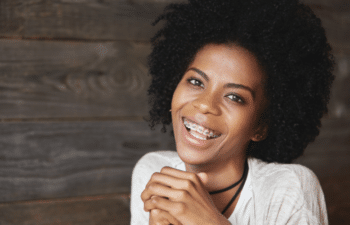 Smiling woman with natural hair wearing white shirt against wooden background