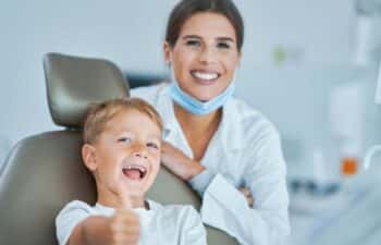 Young boy smiling in dental chair with dentist behind him in Marietta office.