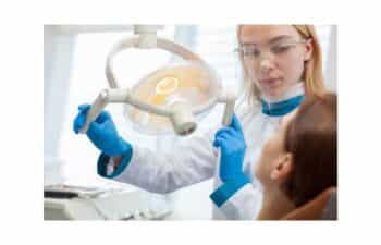 Female dentist in blue gloves adjusting overhead dental light during patient treatment in Marietta.