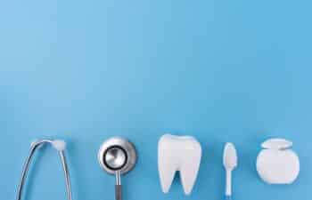 Dental tools and tooth model arranged on blue background representing oral care.