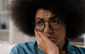 Worried young patient with glasses considering dental emergency care options.