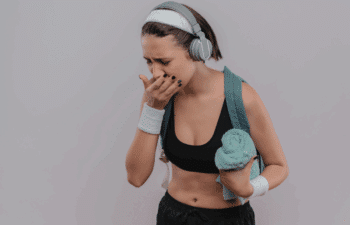 Athletic woman in sports gear experiencing tooth pain during workout, illustrating dental injury during sports.