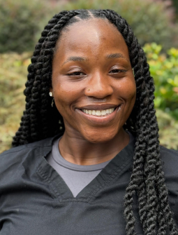 Smiling woman with braided hair in professional portrait outdoors, dental practice staff member.