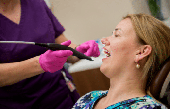 Dentist in pink gloves examining patient's teeth during dental checkup at Marietta practice.