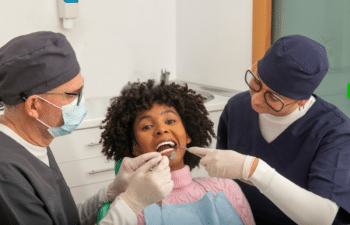 Smiling patient receiving dental examination from two dentists in Marietta, GA.