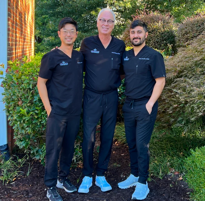 Three Gilreath Family Dentistry dentists standing together outdoors in black scrubs.